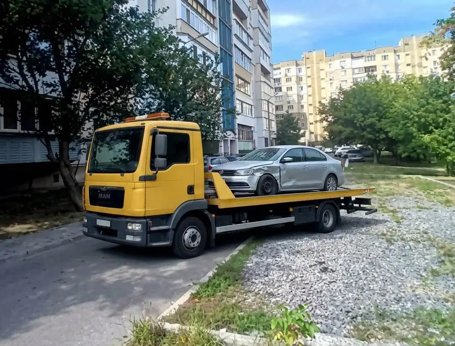 Евакуатор MAN із завантаженим Volkswagen у дворі багатоповерхівки в Борисполі
